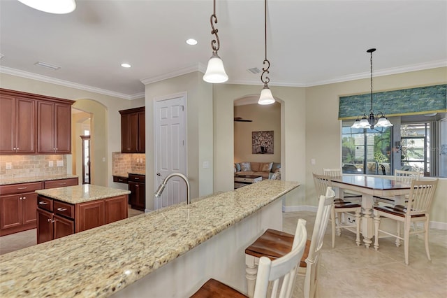 kitchen featuring hanging light fixtures, a kitchen island, backsplash, and light stone counters