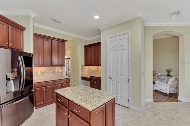 kitchen with stainless steel refrigerator with ice dispenser, a center island, light tile patterned flooring, and light stone counters