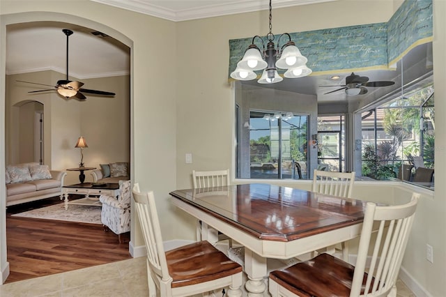 tiled dining area with ornamental molding and ceiling fan with notable chandelier