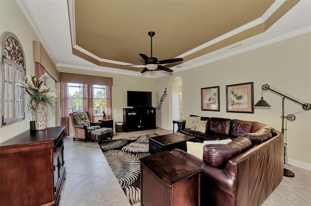 tiled living room with ornamental molding, a raised ceiling, and ceiling fan