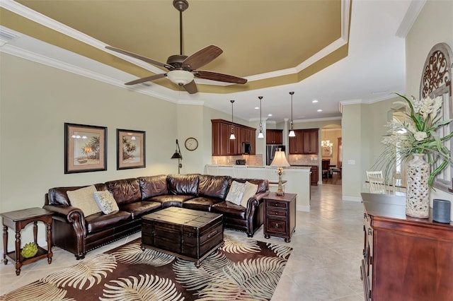 tiled living room featuring ceiling fan, ornamental molding, and a raised ceiling