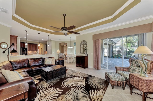 tiled living room featuring crown molding, a raised ceiling, and ceiling fan