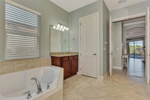 bathroom featuring tiled tub, vanity, and tile patterned floors