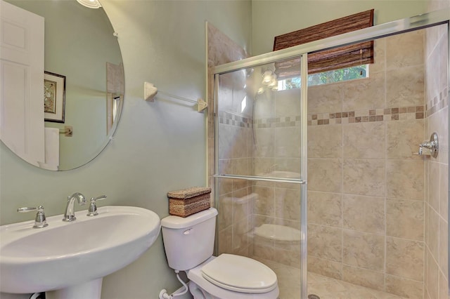 bathroom featuring an enclosed shower, sink, and toilet