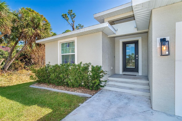 152 Apollo Dr, Rotonda West, FL 33947 - entrance to property featuring stucco siding and a lawn