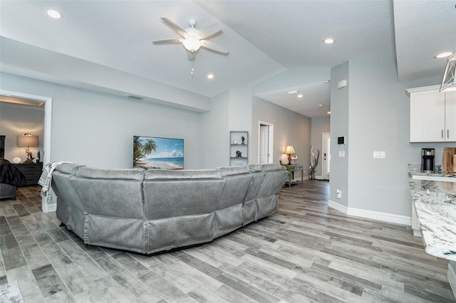 living room with ceiling fan, light wood-type flooring, and vaulted ceiling