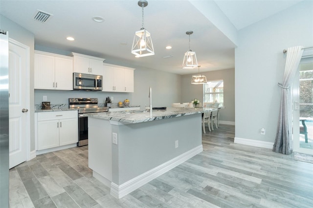 152 Apollo Dr, Rotonda West, FL 33947 - kitchen with stainless steel appliances, light stone countertops, white cabinets, recessed lighting, and hanging light fixtures