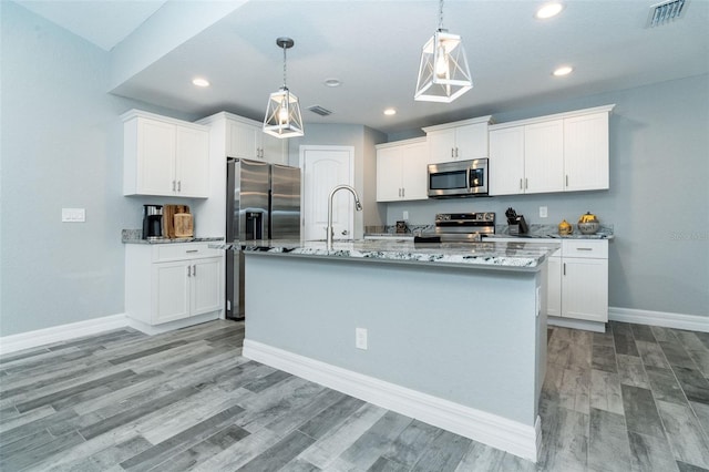 kitchen featuring white cabinets, stainless steel appliances, and an island with sink