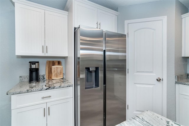 152 Apollo Dr, Rotonda West, FL 33947 - kitchen with stainless steel fridge, white cabinets, and light stone countertops