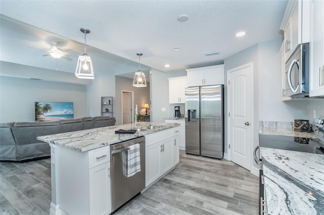 kitchen with white cabinetry, appliances with stainless steel finishes, light stone countertops, hanging light fixtures, and a center island