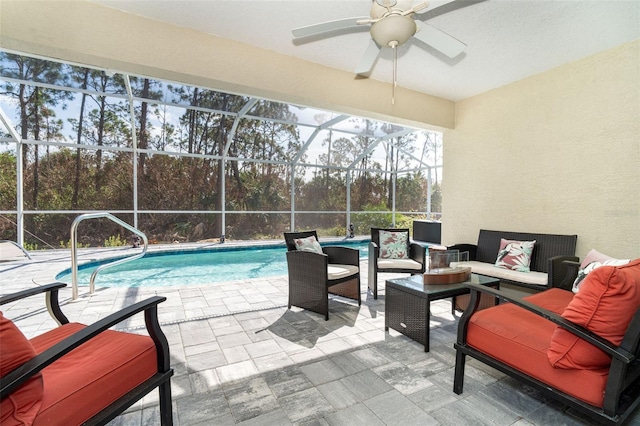 view of swimming pool featuring glass enclosure, outdoor lounge area, a patio, and ceiling fan