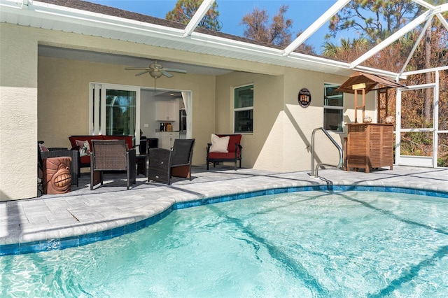 view of pool featuring glass enclosure, a patio area, and ceiling fan