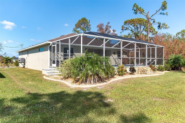 152 Apollo Dr, Rotonda West, FL 33947 - rear view of property with stucco siding, a lawn, and glass enclosure
