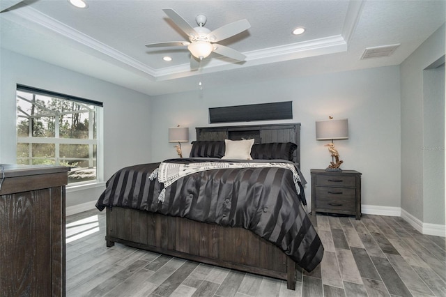 bedroom featuring ceiling fan, ornamental molding, a tray ceiling, and wood-type flooring