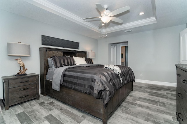 bedroom with a textured ceiling, light hardwood / wood-style flooring, ceiling fan, and a raised ceiling