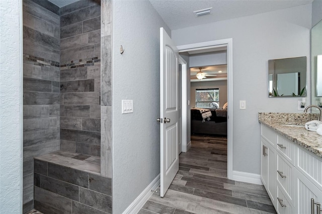 bathroom with vanity, wood-type flooring, ceiling fan, and a textured ceiling