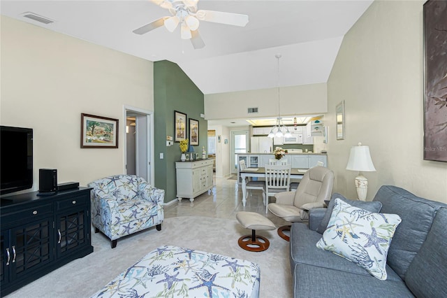 carpeted living room featuring ceiling fan with notable chandelier and high vaulted ceiling