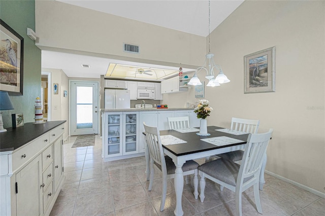 tiled dining space featuring a chandelier and vaulted ceiling