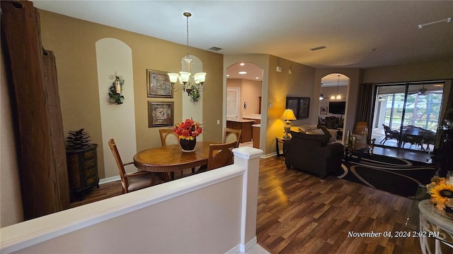 dining space featuring dark wood-type flooring and a notable chandelier