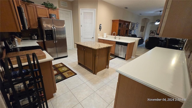 kitchen featuring stainless steel appliances, sink, a kitchen island, and light tile patterned floors