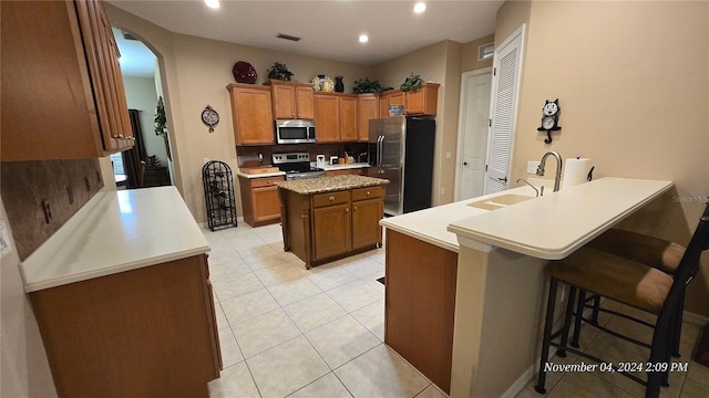 kitchen featuring stainless steel appliances, backsplash, sink, a kitchen breakfast bar, and a center island