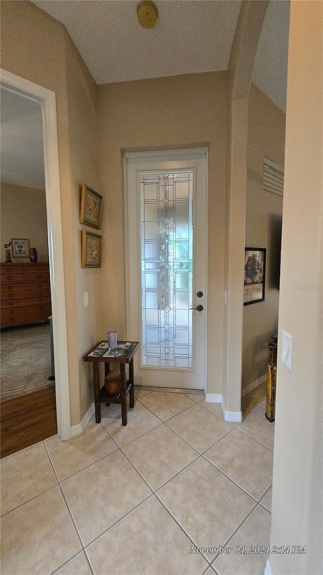 foyer entrance with a textured ceiling and light tile patterned floors