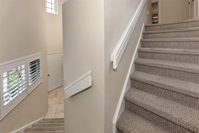 stairway featuring a wealth of natural light and tile patterned floors