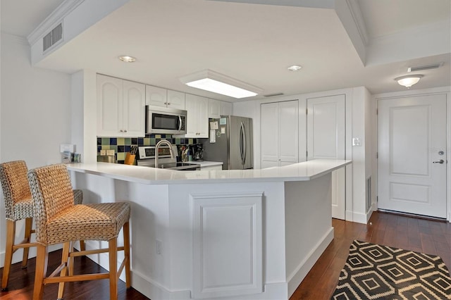 kitchen with kitchen peninsula, white cabinetry, a breakfast bar, and stainless steel appliances