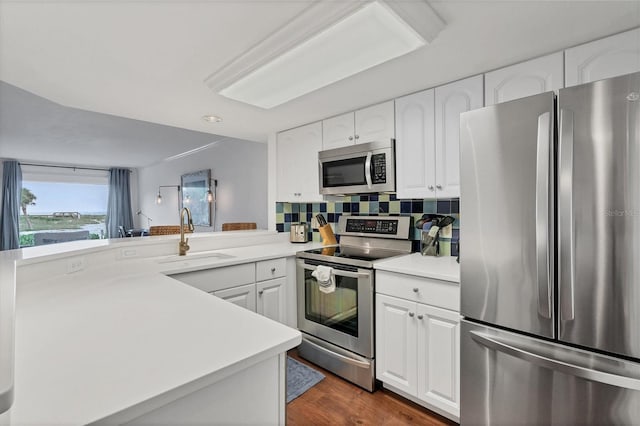 kitchen featuring white cabinetry, sink, dark wood-type flooring, kitchen peninsula, and appliances with stainless steel finishes