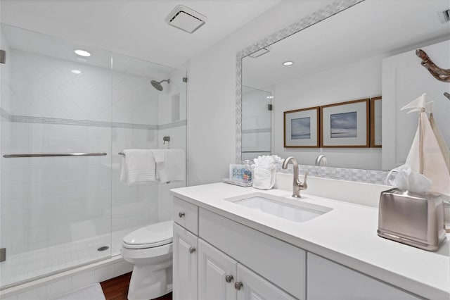 bathroom featuring hardwood / wood-style floors, vanity, toilet, and a shower with door