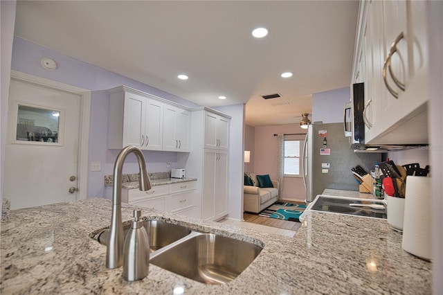 kitchen featuring light stone counters, sink, white cabinets, and stainless steel appliances