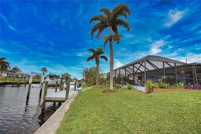 dock area with a lawn, glass enclosure, and a water view