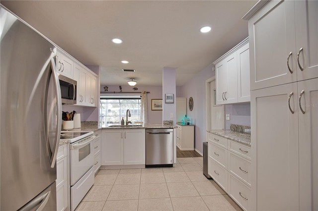 kitchen featuring white cabinets, sink, light tile patterned flooring, light stone counters, and stainless steel appliances