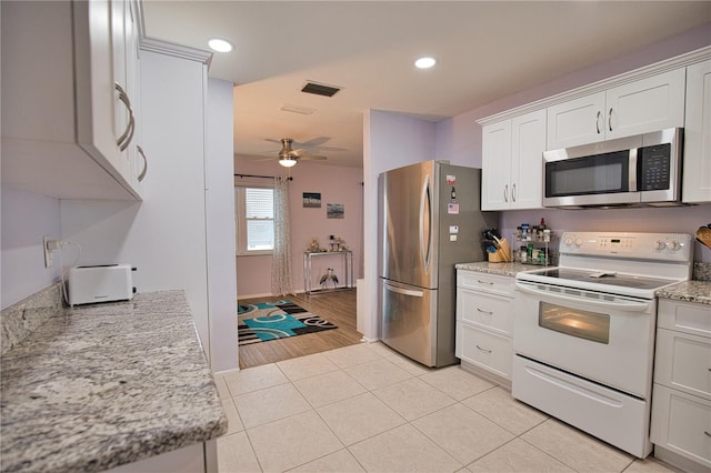 kitchen featuring appliances with stainless steel finishes, light stone counters, ceiling fan, white cabinetry, and light tile patterned flooring