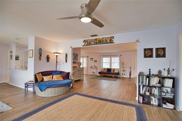 living room featuring ceiling fan, wood-type flooring, and sink