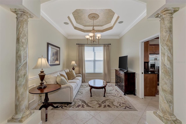 living room featuring ornamental molding, a notable chandelier, a raised ceiling, and decorative columns