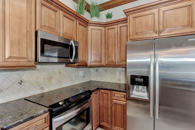 kitchen featuring decorative backsplash, appliances with stainless steel finishes, and dark stone counters