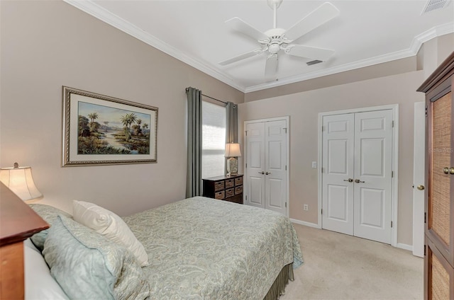 carpeted bedroom with ornamental molding, ceiling fan, and multiple closets