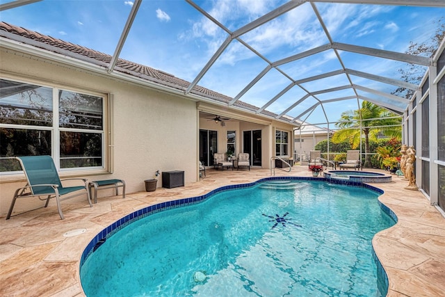 view of swimming pool featuring ceiling fan, glass enclosure, an in ground hot tub, and a patio area