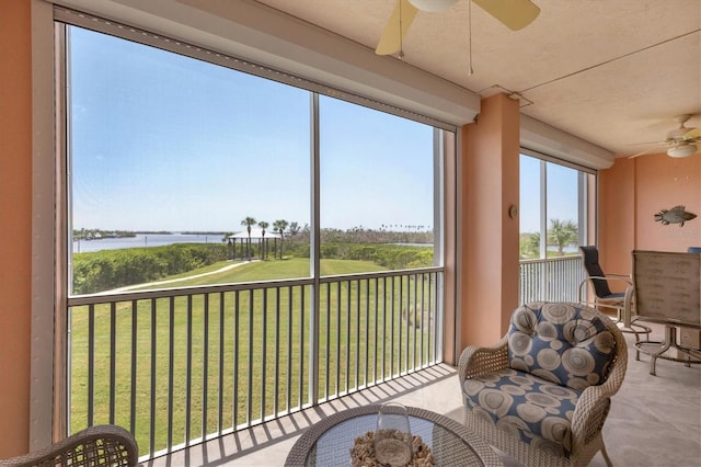 sunroom / solarium with a water view and ceiling fan