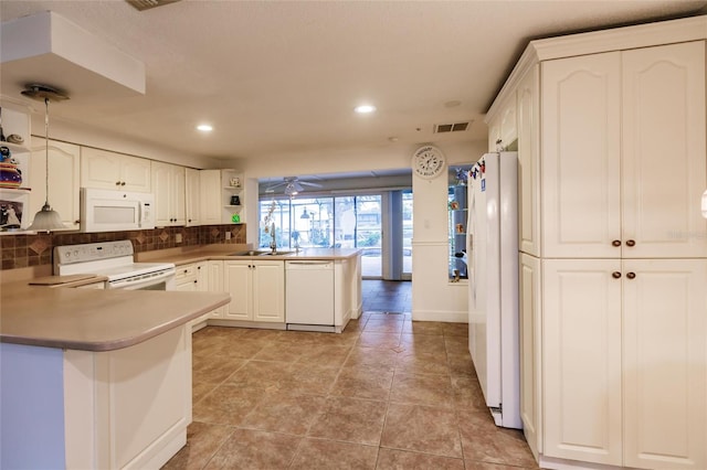 kitchen with decorative light fixtures, white appliances, decorative backsplash, sink, and kitchen peninsula