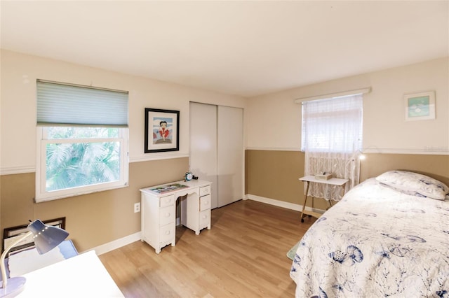 bedroom featuring a closet, light wood-type flooring, and multiple windows