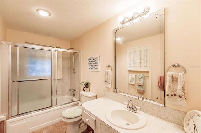 full bathroom featuring vanity, a textured ceiling, tile patterned flooring, toilet, and combined bath / shower with glass door