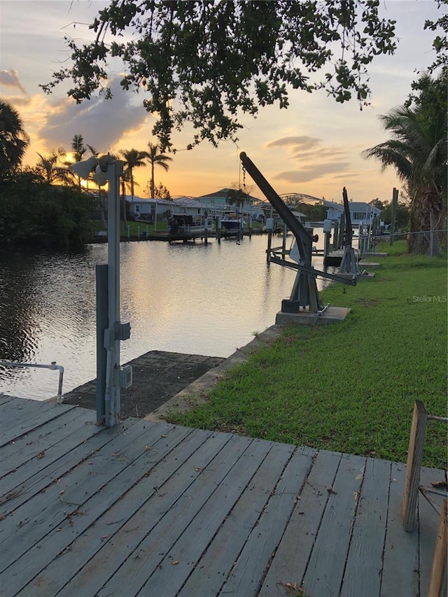 dock area with a lawn and a water view