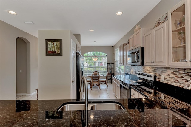 kitchen featuring dark stone countertops, hanging light fixtures, sink, and stainless steel appliances