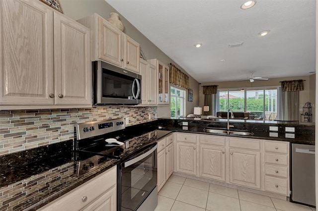 kitchen featuring decorative backsplash, sink, ceiling fan, appliances with stainless steel finishes, and dark stone countertops