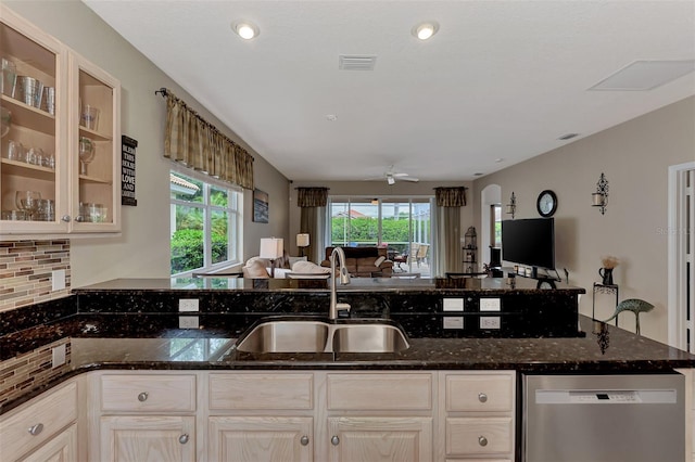 kitchen with stainless steel dishwasher, dark stone counters, a healthy amount of sunlight, and sink