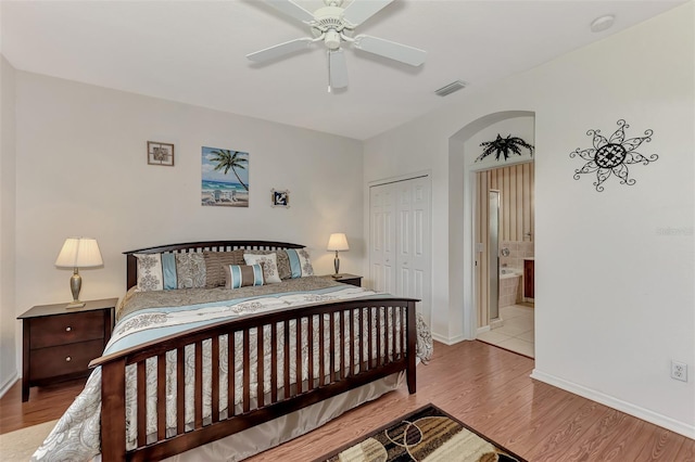 bedroom featuring a closet, light wood-type flooring, ceiling fan, and ensuite bathroom