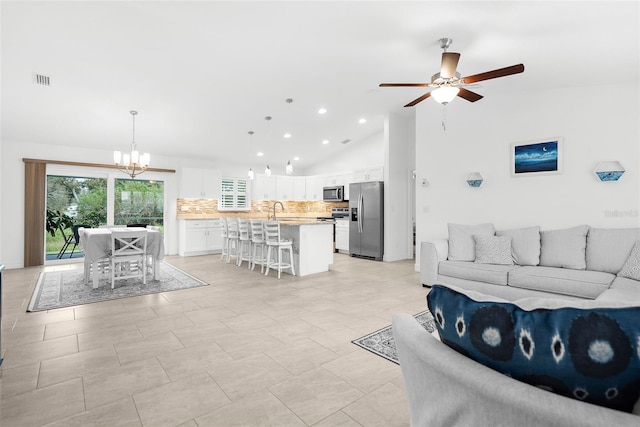 living room featuring ceiling fan with notable chandelier, sink, and high vaulted ceiling