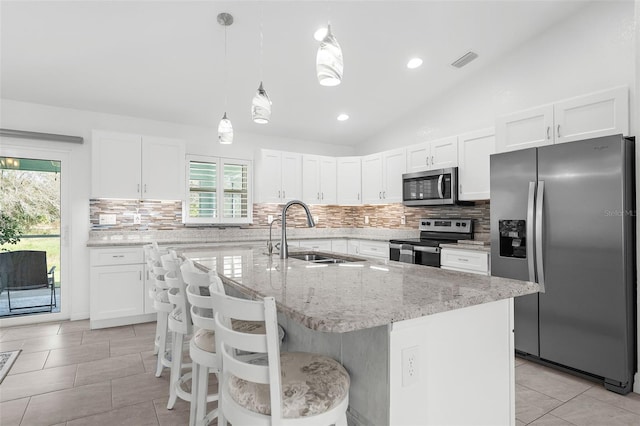 kitchen with appliances with stainless steel finishes, decorative light fixtures, sink, an island with sink, and lofted ceiling